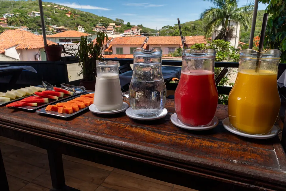 Sucos no terraço do café, com os morros e as casas de Búzios ao fundo