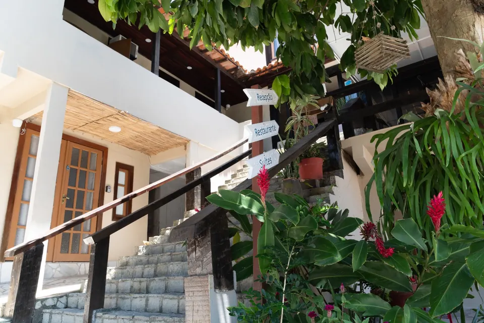 Entrada com escada, plantas e placas indicando recepção e quartos