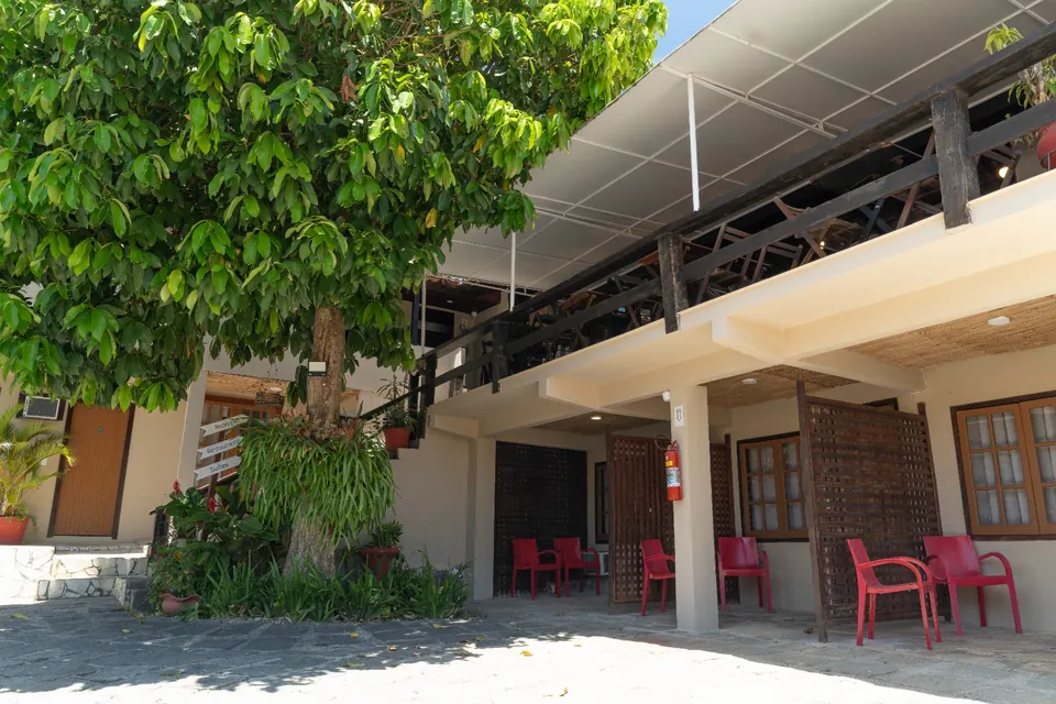 Fachada da pousada com varandas e cadeiras vermelhas