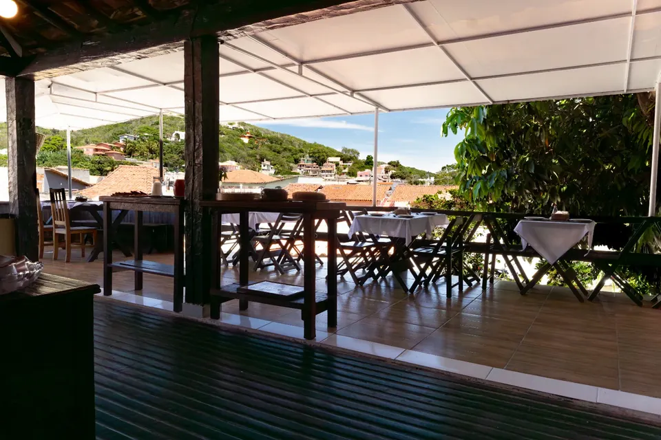 Terraço coberto com mesas e vista para os morros de Búzios