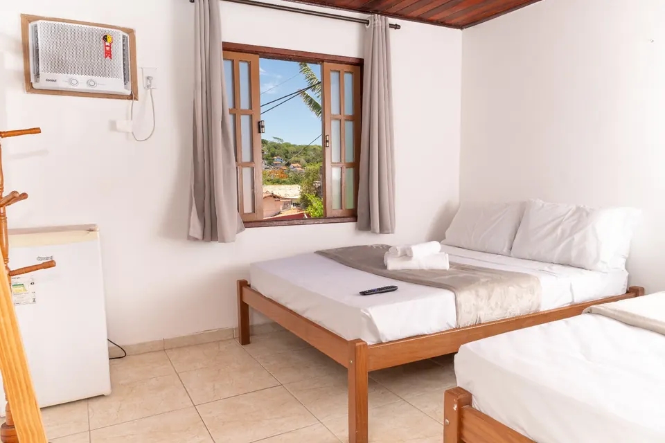 Quarto Triplo com cama de casal, cama de solteiro e janela para os morros